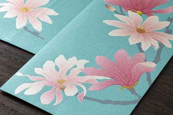 Close-up of a multipurpose envelope showing a teal background with a pink magnolia-style floral pattern.