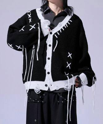 Black cardigan with white stitch details, front buttons, distressed edges, and hanging threads shown on a model.