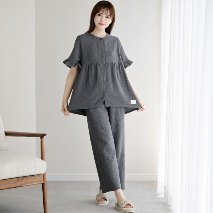 Woman modeling a gray two-piece women's pajama set (top and pants) standing indoors.