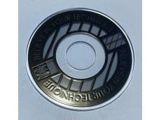 Close-up photo of a round joystick lever disk in stealth black with a central hole, cutout sections, and embossed text.