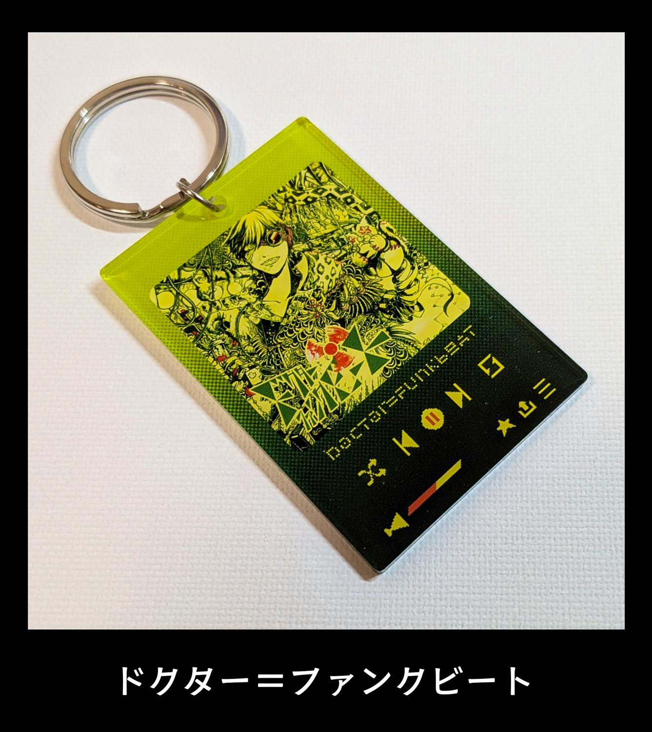 Close photo of a yellow-green music player–style acrylic keychain with a metal split ring resting on a white surface.