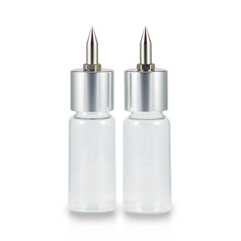 Two clear glass nozzle bottles with silver caps and pointed metal nozzles shown on a white background.