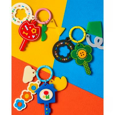 Colorful rubber keychain charms and rings arranged on a multicolored yellow, blue, and orange background.