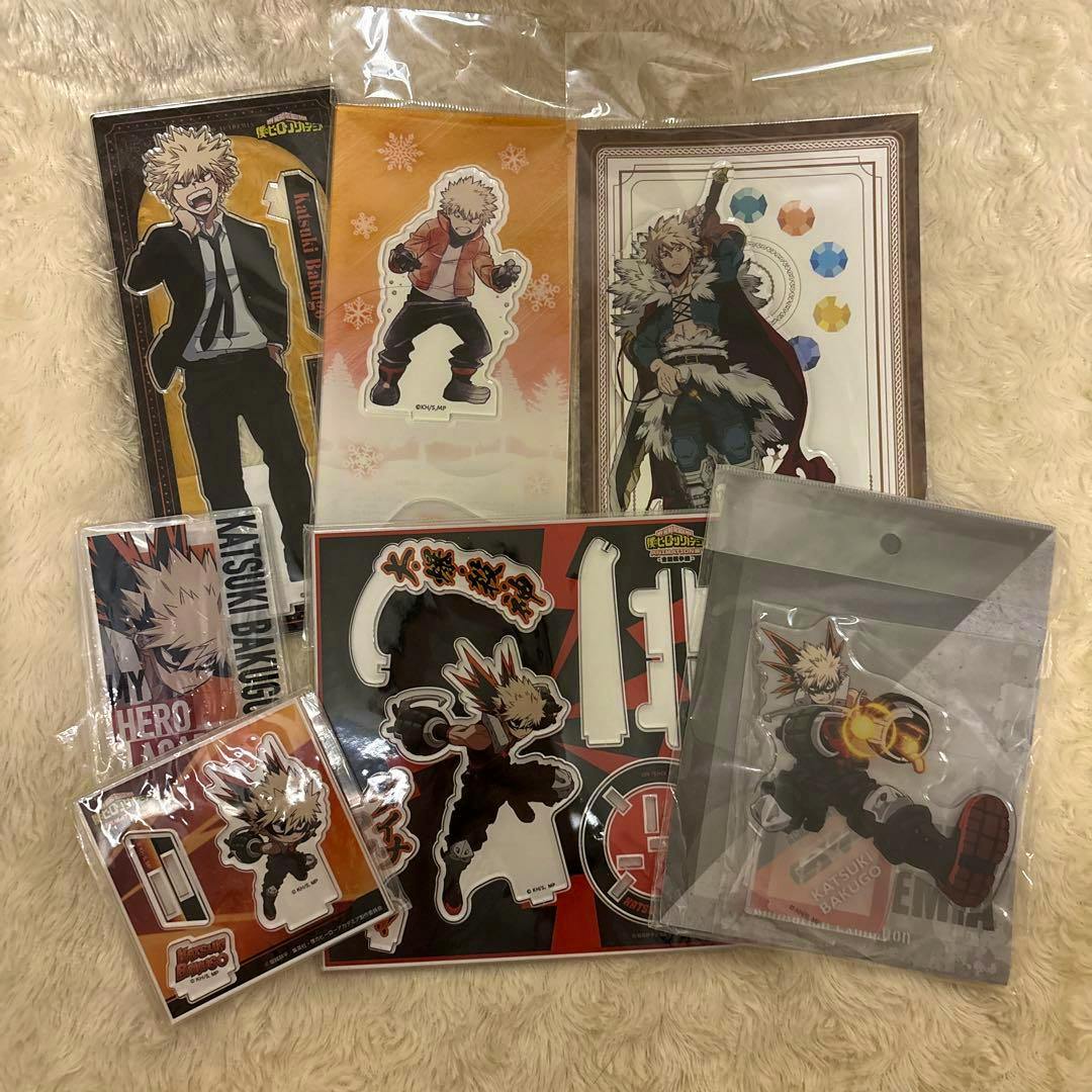 Multiple Bakugou Katsuki acrylic decorative stands in various packaging arranged on a beige fuzzy surface.