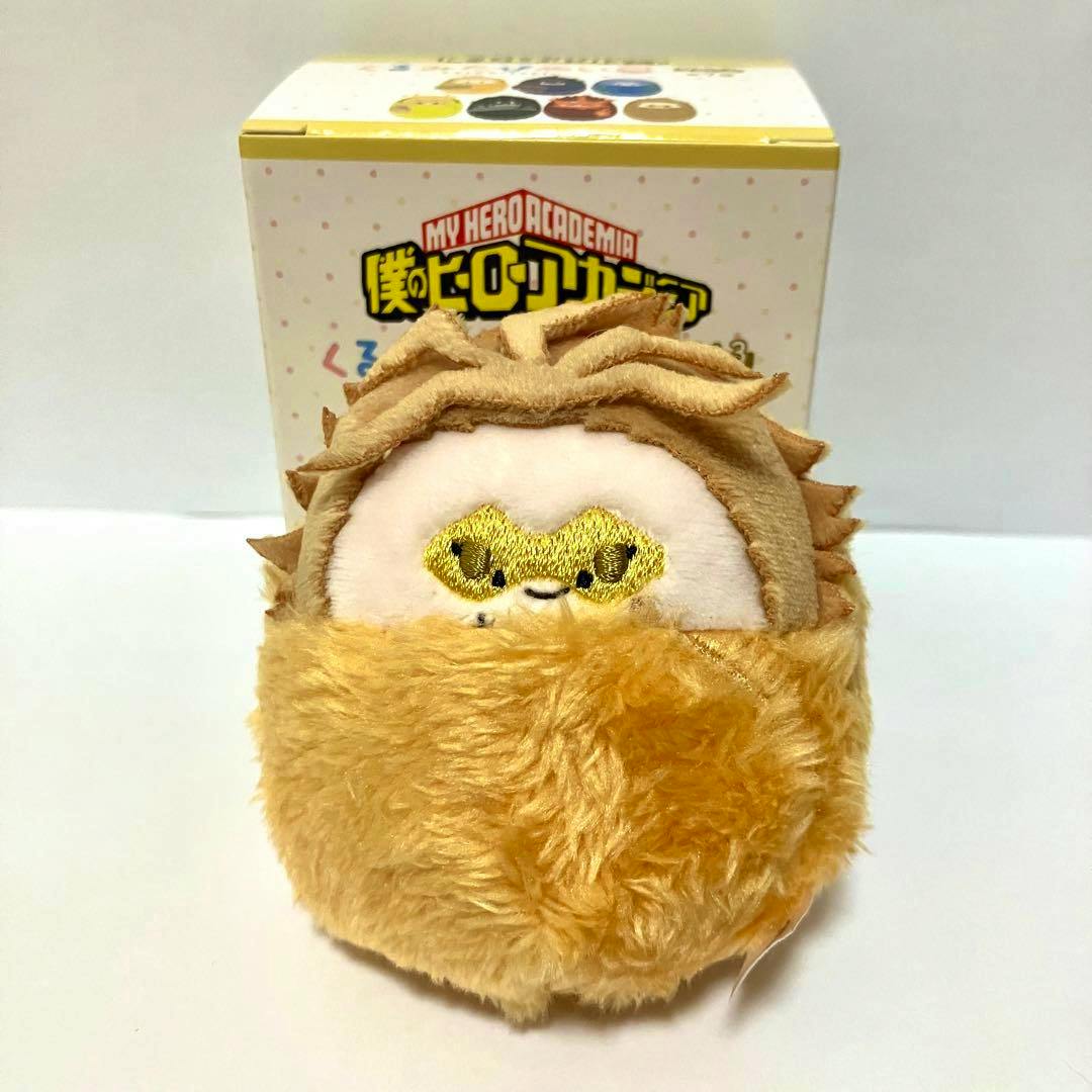 A round Hawks plush (My Hero Academia) with a gold-stitched eye mask, photographed in front of its product box.
