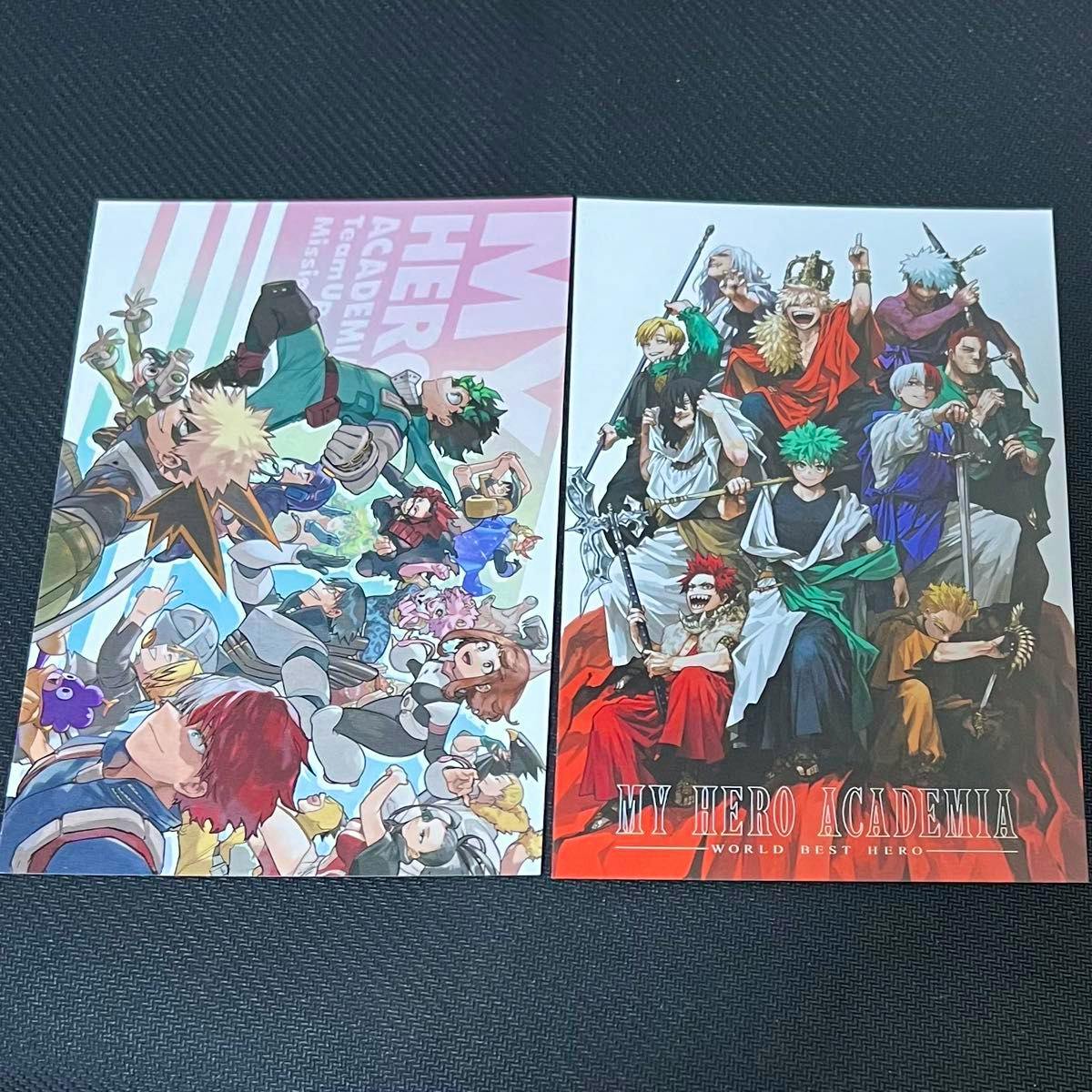 Two My Hero Academia postcards from the postcard set showing character illustrations placed on a dark textured surface.