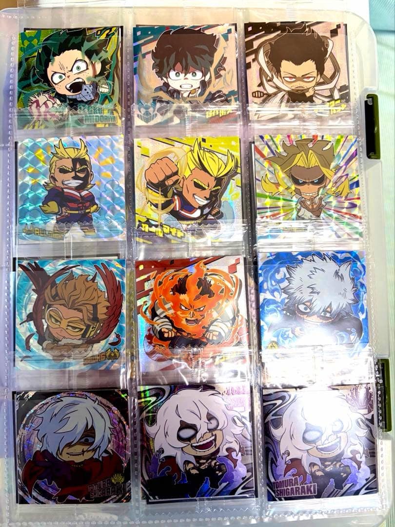 Close-up photo of many My Hero Academia wafer stickers displayed in plastic binder pockets, showing chibi character designs with holographic backgrounds.