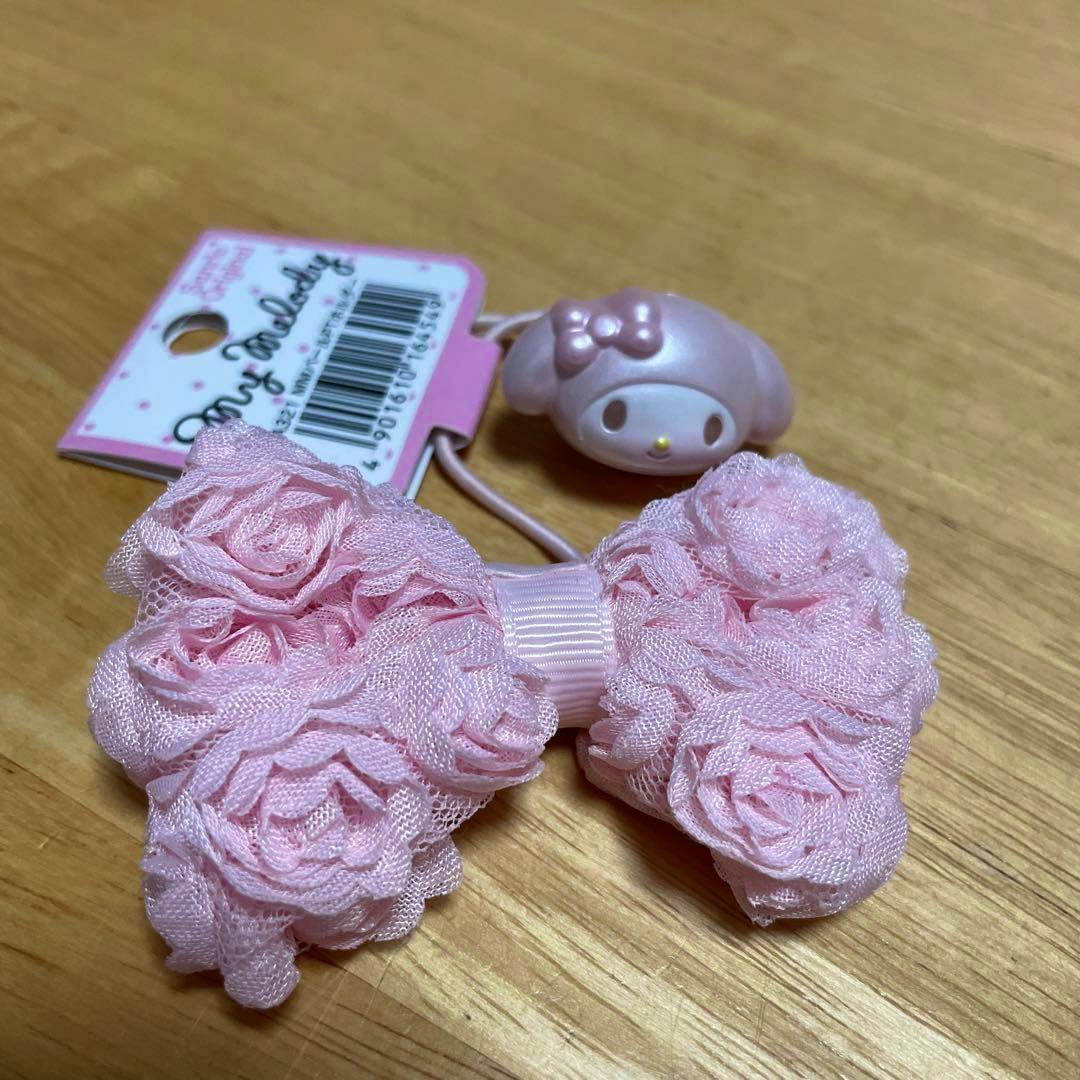 Pink My Melody pearl ponytail holder hair tie with a lace bow and character charm on a wooden surface.