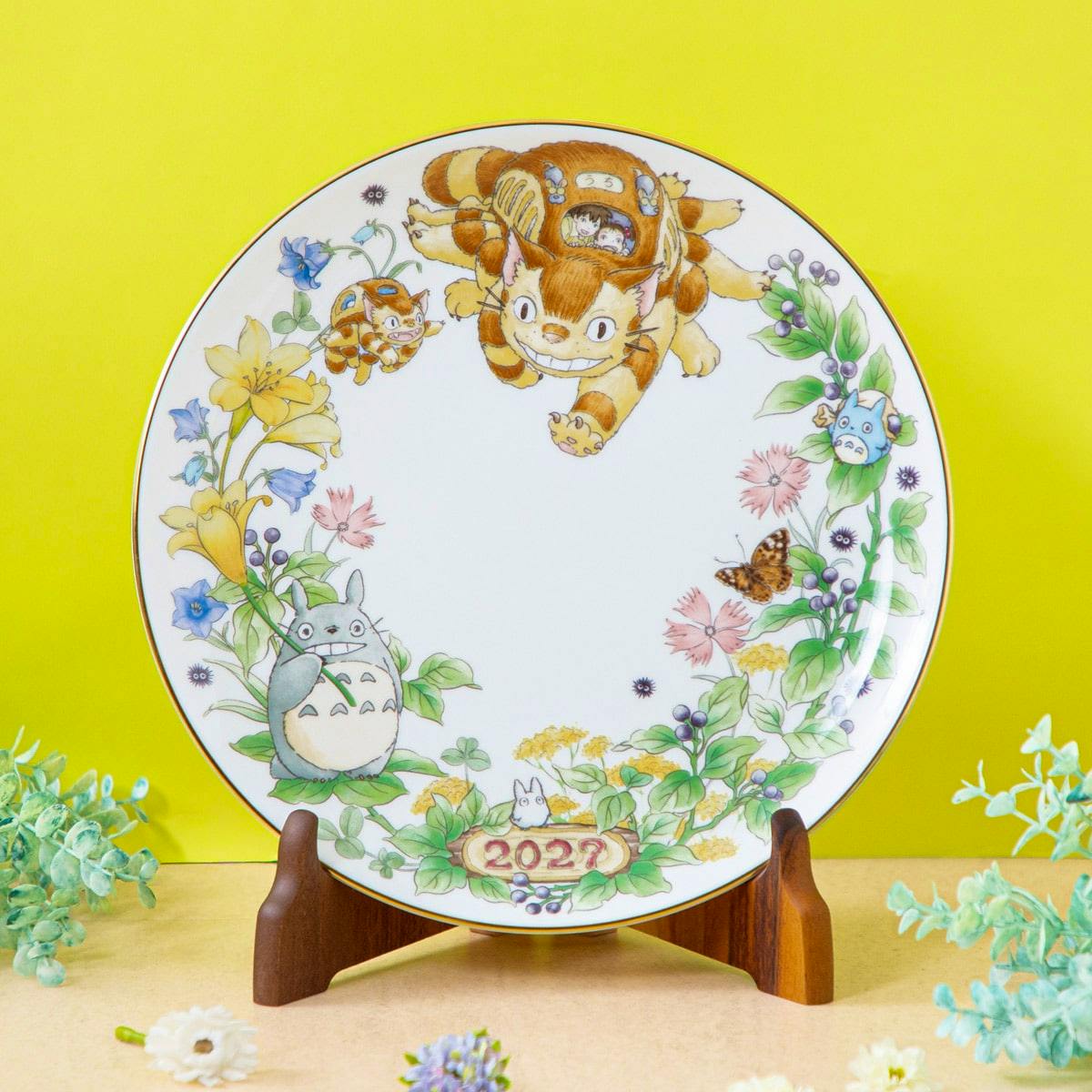 Porcelain 2027 year decorative plate featuring Totoro characters and floral border displayed on a wooden stand.