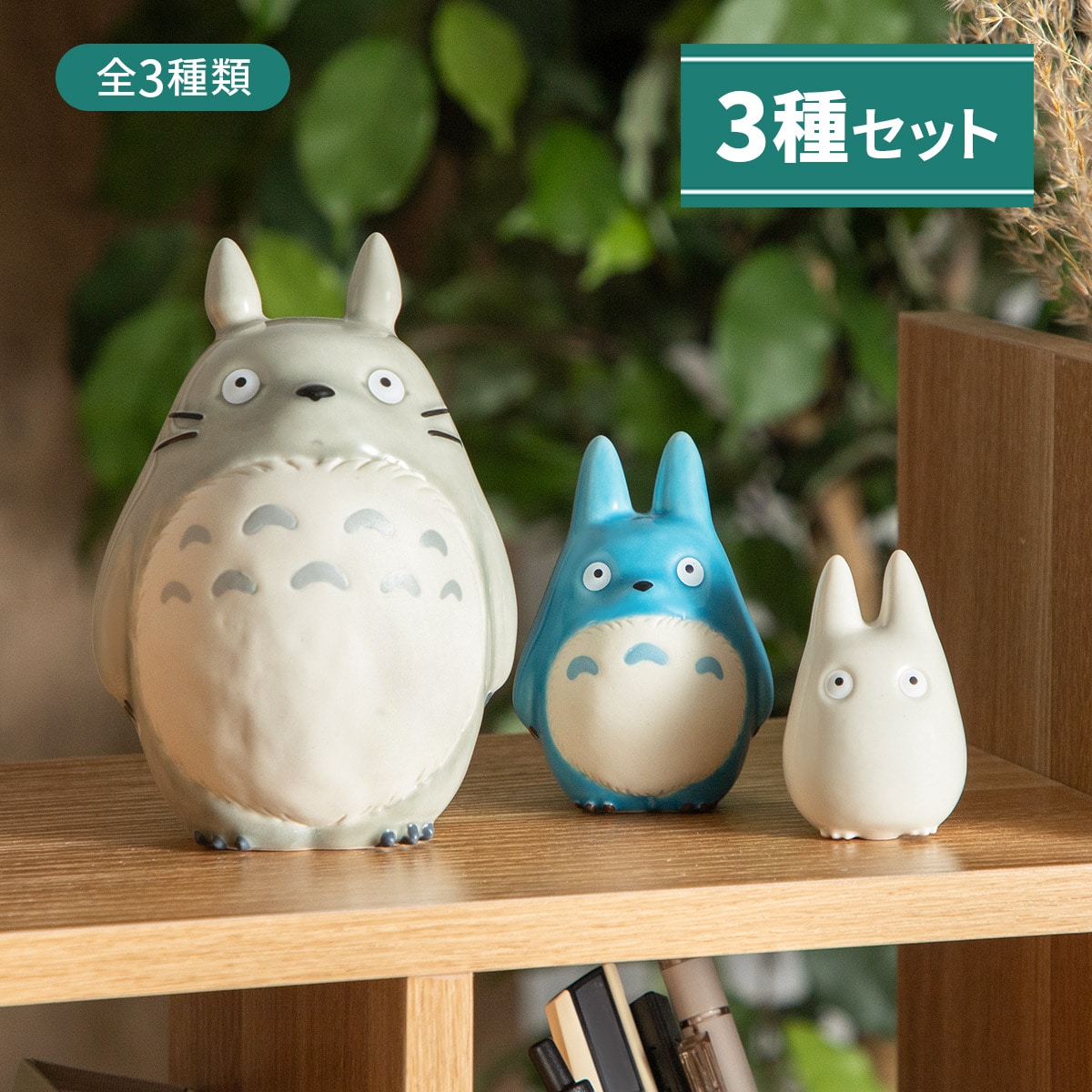 Three ceramic Totoro figures (large gray, medium blue, small white) displayed on a wooden shelf.