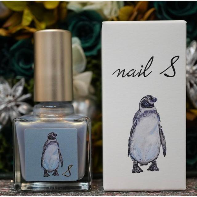 Glass bottle of 'nail S' luminous blue nail polish next to its white box, both showing a penguin illustration.