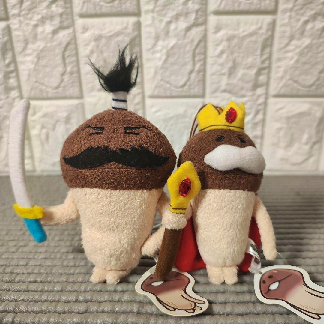 Two おさわり探偵なめこ plush toys (King and General) photographed side by side, one holding a sword and the other wearing a crown and cape.