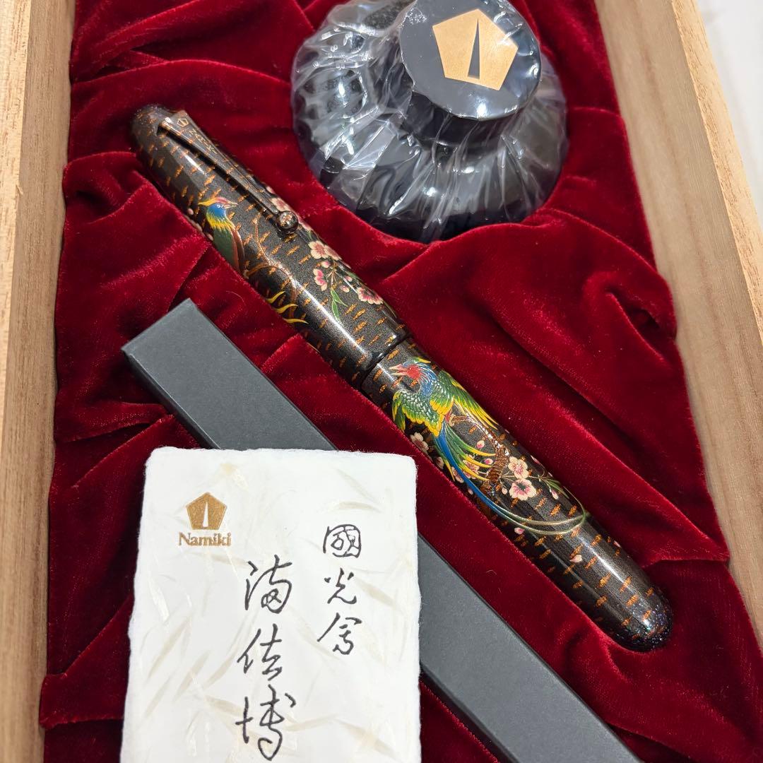 Namiki fountain pen with cherry blossom and bird maki-e design displayed in a red velvet-lined wooden box alongside an ink bottle and certificate.