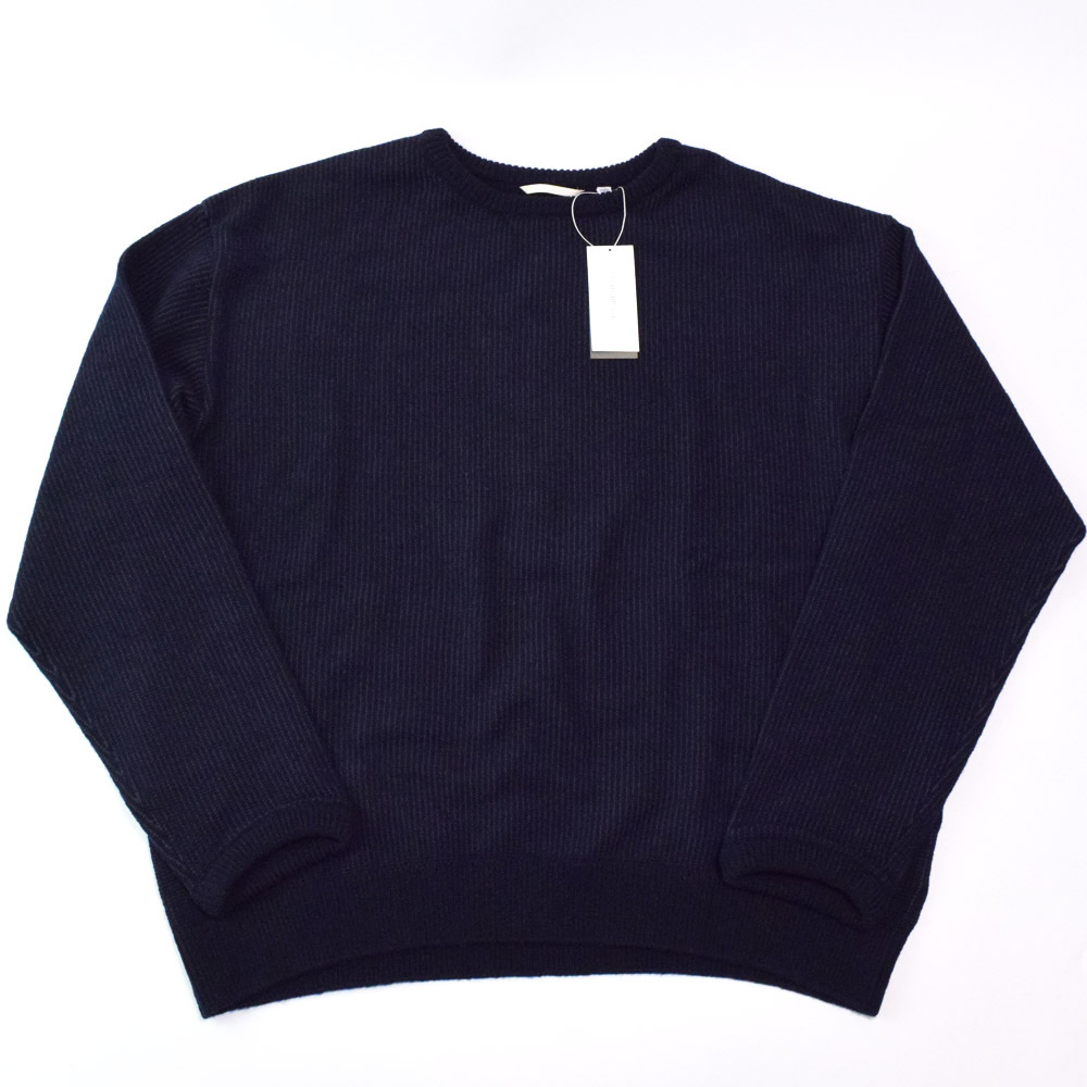 Flat-lay navy wool crewneck sweater with an attached tag visible.