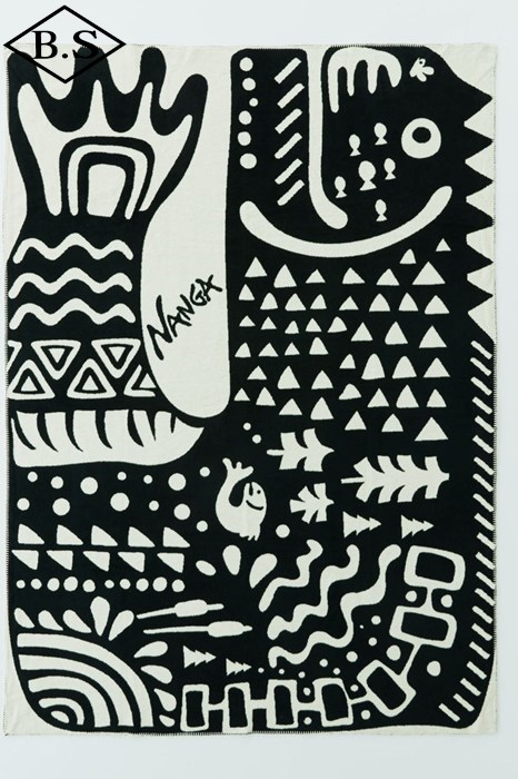 Flat-lay photo of a black-and-white cotton blanket showing an abstract fish motif and geometric patterns.