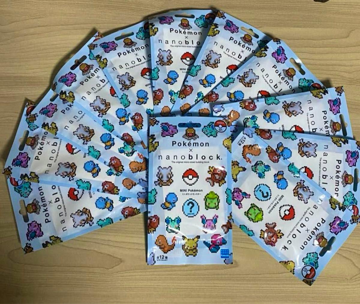 Multiple sealed Pokémon × nanoblock mini blind bags fanned out on a wooden surface.
