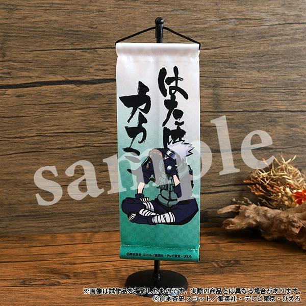 Mini hanging scroll (mini tapestry) of Hatake Kakashi from NARUTO displayed on a small black stand against a wooden background.