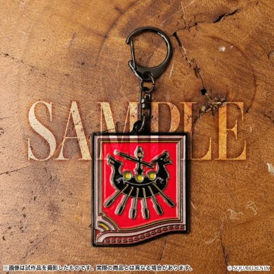 A metal keychain with a red square crest design photographed on a wooden surface.