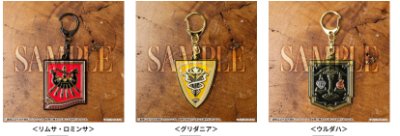 Three metal national-flag keychains displayed on a wooden surface.