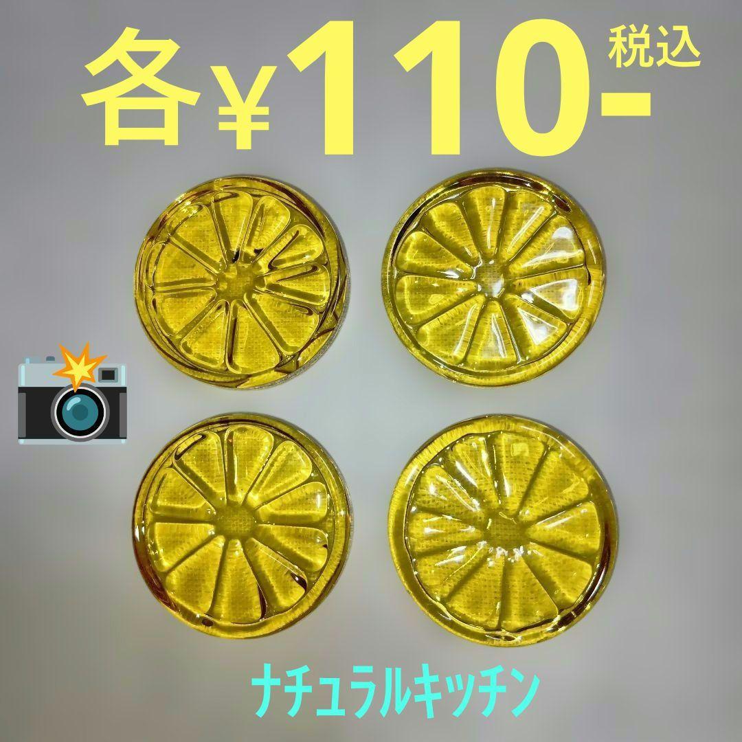Four yellow glass lemon-shaped chopstick rests arranged on a light background.