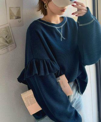 Model wearing the navy women's blouse (polyester) with long ruffled sleeves and contrast stitching, shown from the waist up.