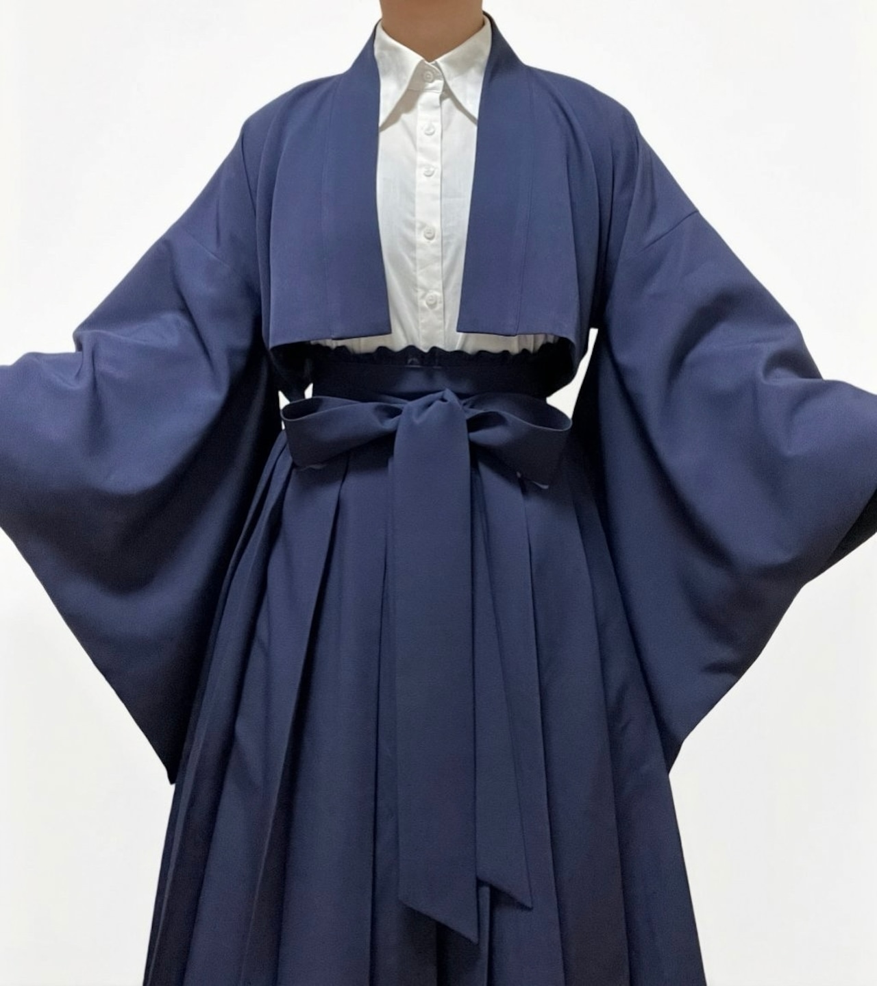 Front view of a model wearing the navy short-length haori over a white shirt, showing wide sleeves and a tied waist ribbon.