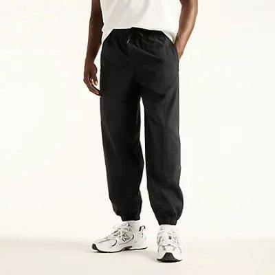 Front view of a model wearing NB GREY men's nylon jogger pants, shown from waist to shoes.