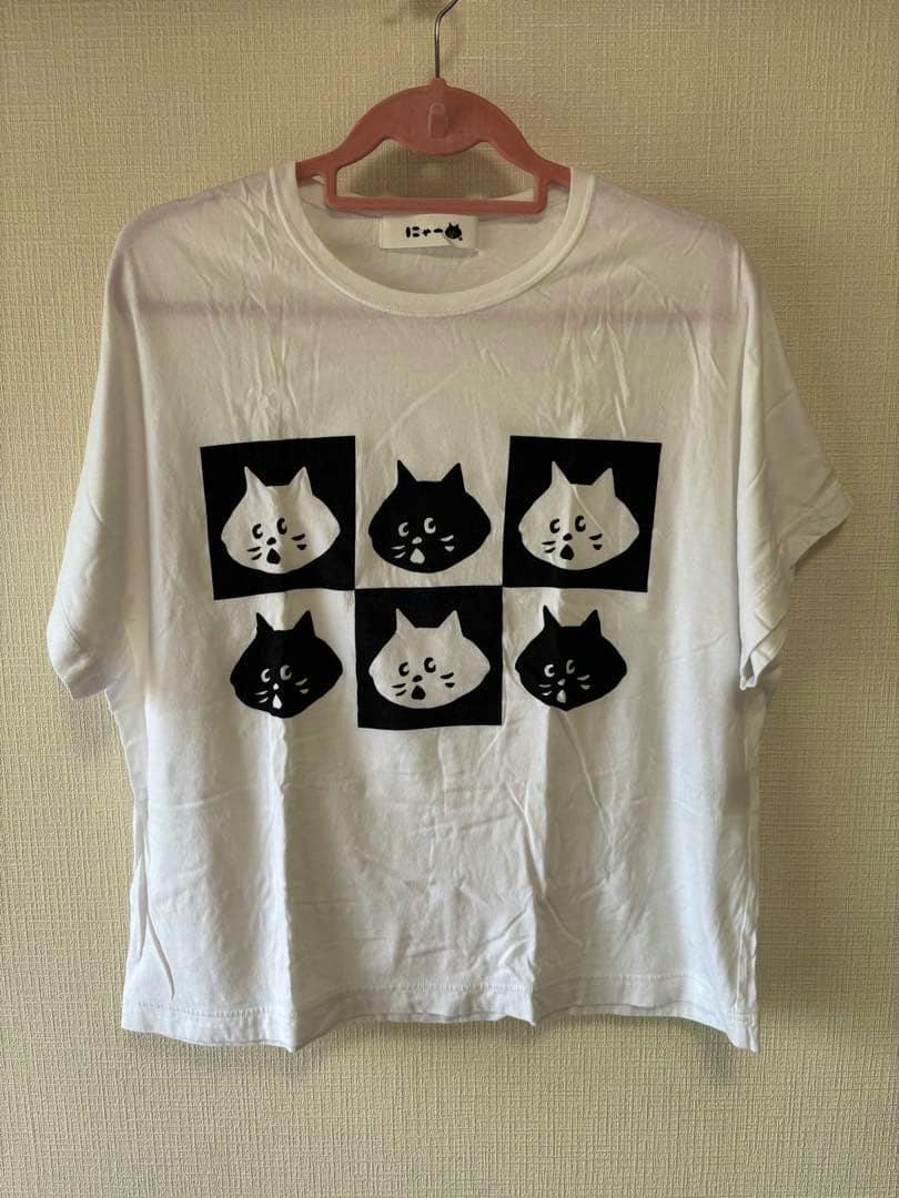 White Né-net short-sleeve T-shirt (M) on a hanger showing the front with six black-and-white cat-face square prints.