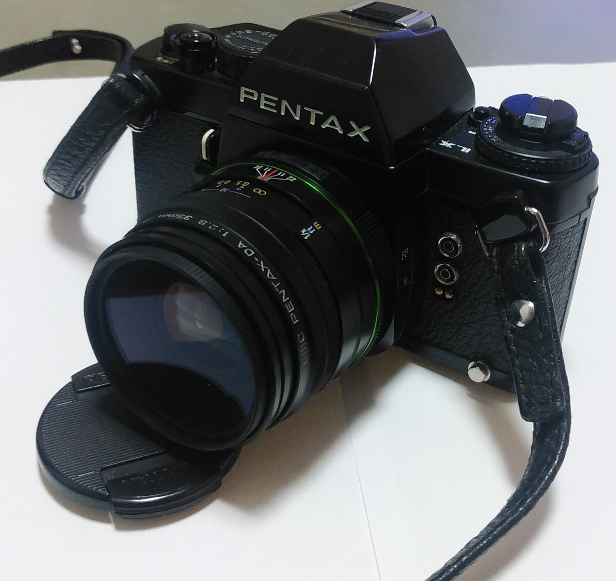 Black Pentax LX film SLR camera with smc PENTAX-DA F2.8 35mm Macro lens attached, shown with lens cap and wrist strap.