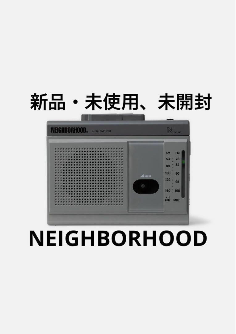 Front view of a gray NEIGHBORHOOD mini boombox radio showing speaker grille and tuning dial with overlaid Japanese and NEIGHBORHOOD text.