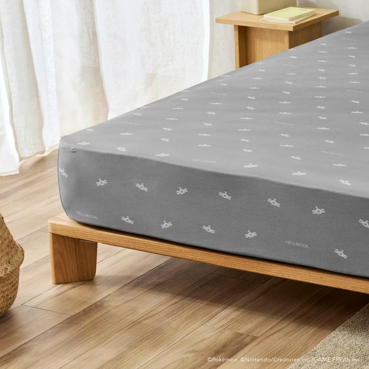 Grey NELL×COIL fitted box sheet with a small white repeating logo pattern fitted on a mattress.