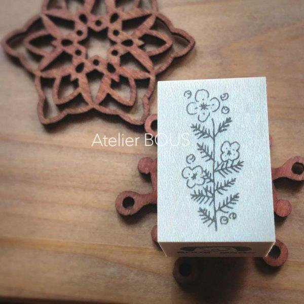 Wooden rectangular stamp block with a nemophila floral design printed on its top, placed on a wooden surface next to decorative wooden pieces.