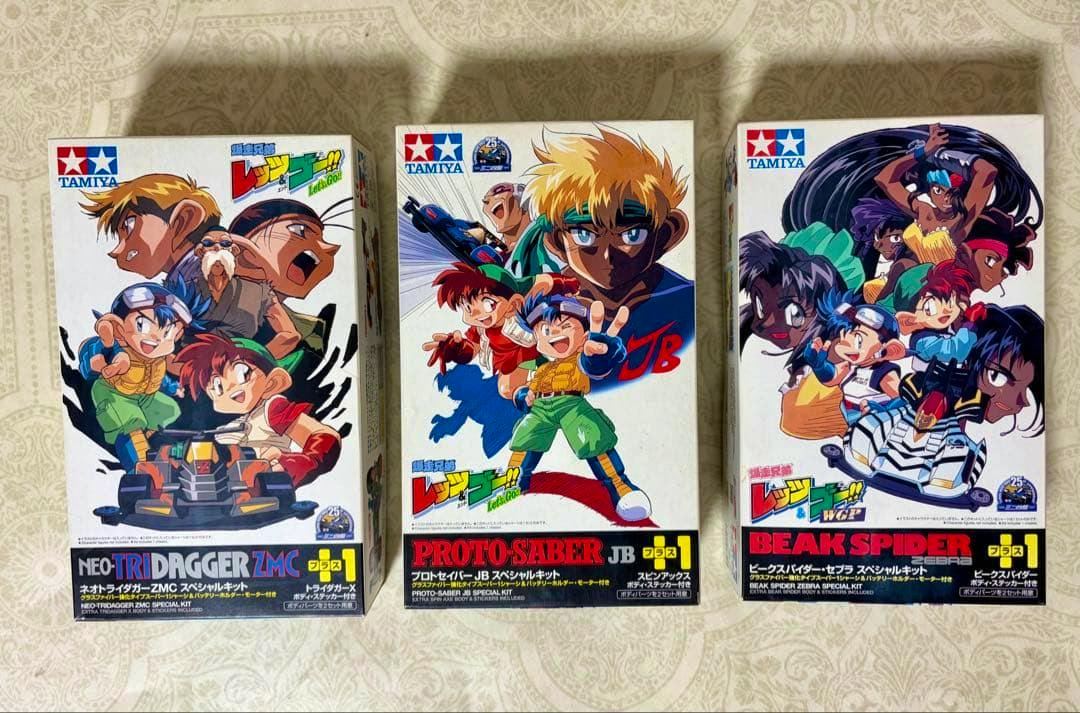 Photo of three Tamiya model kit boxes arranged side by side, with the center box labeled Proto-Saber JB.