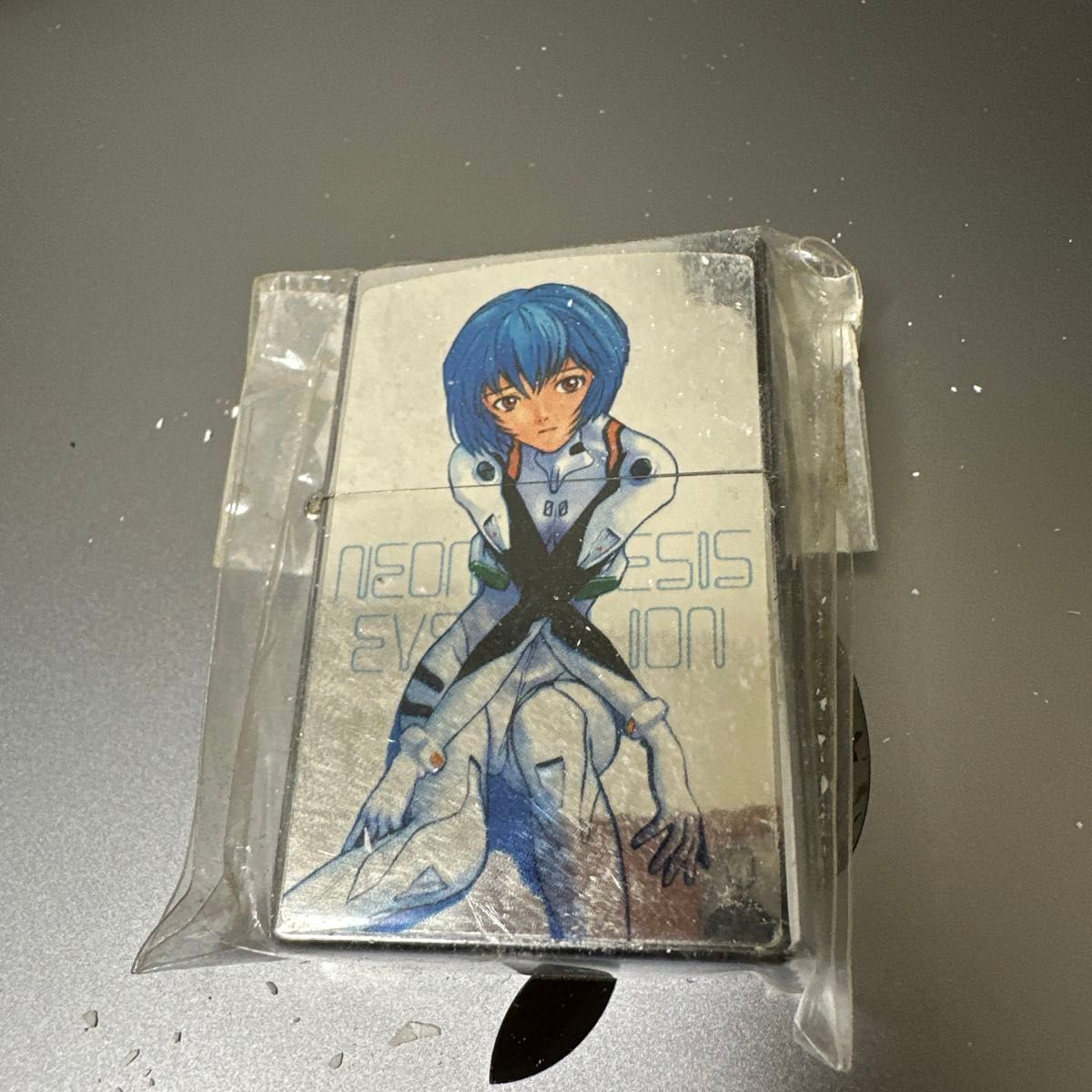 Silver Zippo-style lighter case with Rei Ayanami artwork visible inside sealed plastic packaging.