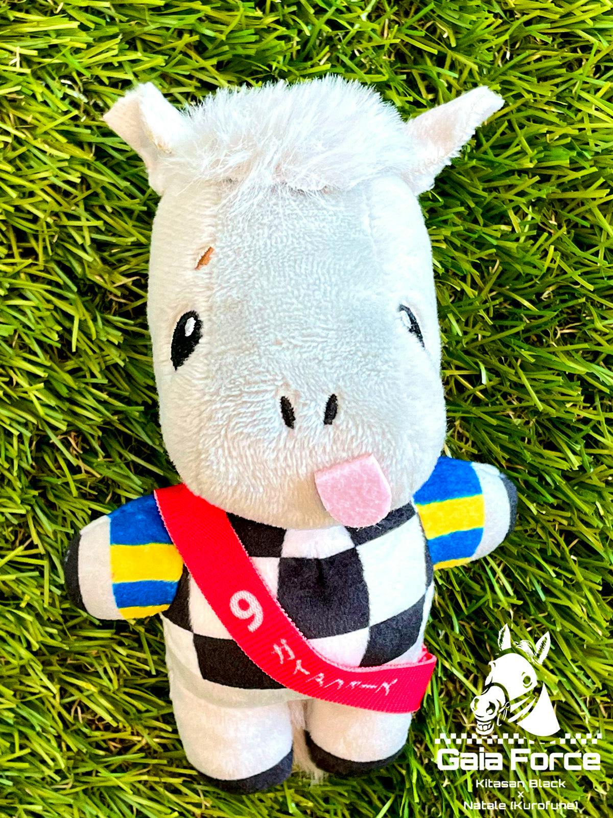 Front-facing Gaia Force plush (white horse) wearing a black-and-white checkered outfit and red sash, photographed on grass.