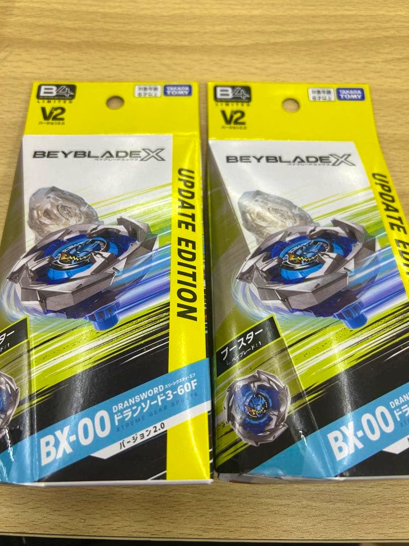 Two boxed Beyblade X BX-00 ドランソード3-60F バージョン2.0 packages shown side by side on a wooden surface.