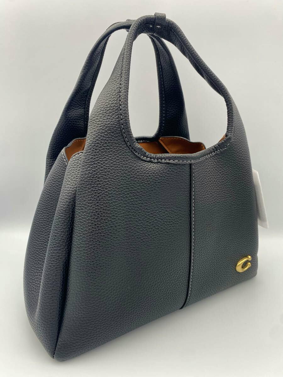 Black COACH bag (canvas) shown from a side angle with twin handles and a small gold "C" emblem.