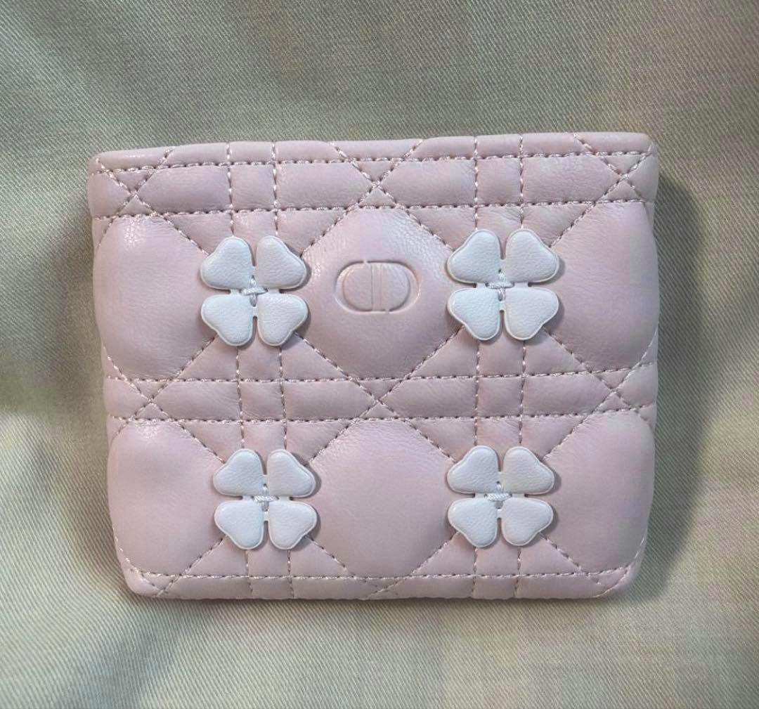 Pink quilted pouch with white four-petal flower appliqués and an embossed CD logo visible on the front.