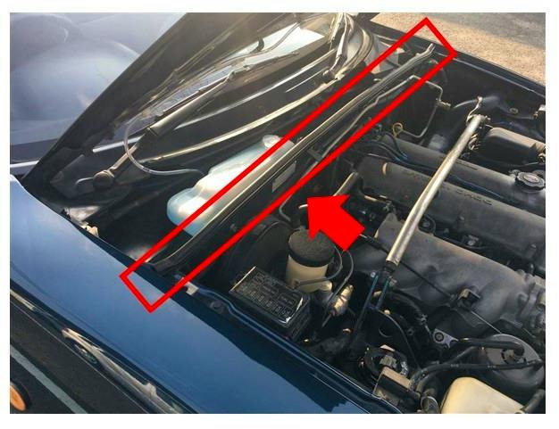 Engine-bay view showing the bonnet weatherstrip on a Mazda NA Roadster highlighted with a red rectangle and arrow.
