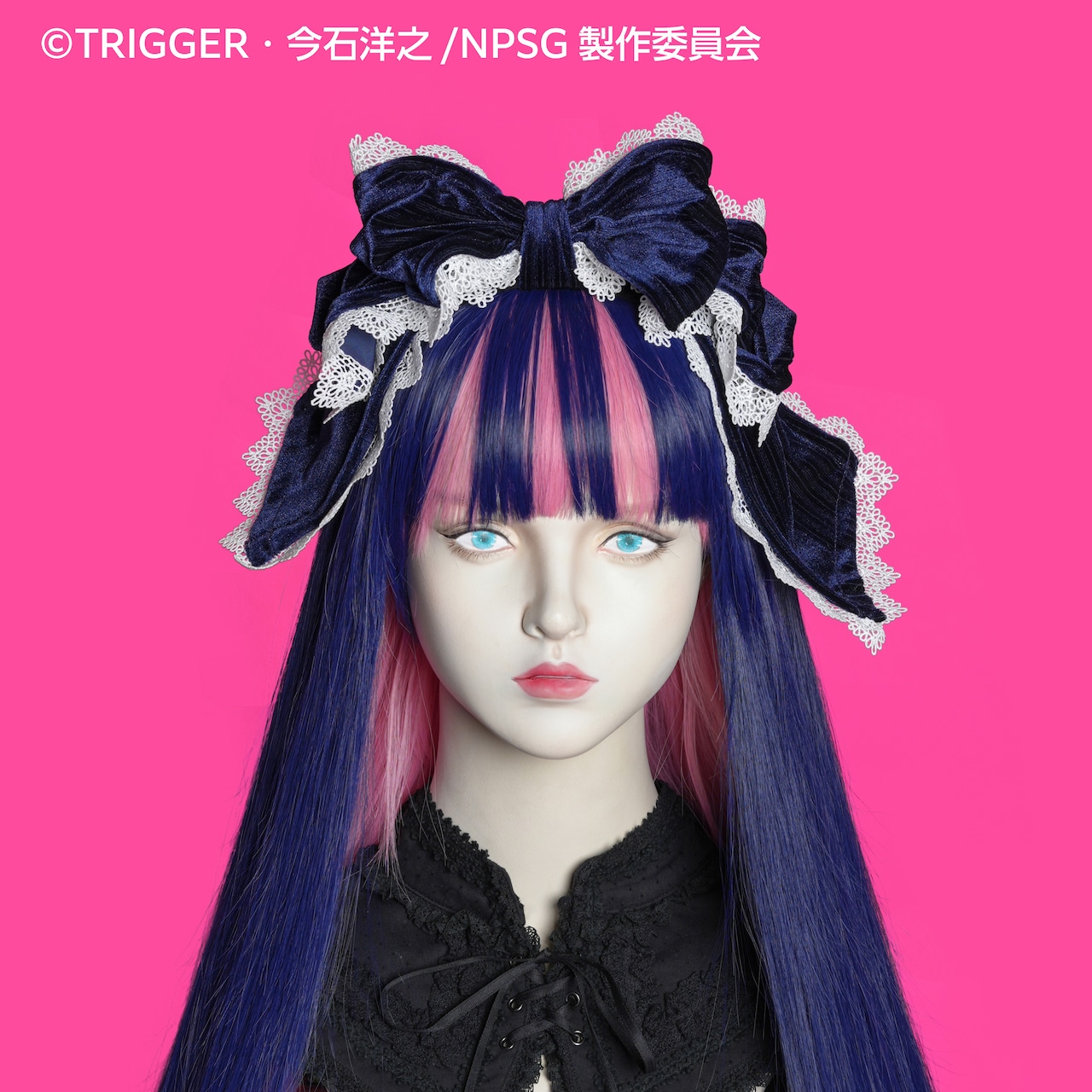 Mannequin head wearing a navy blue ribbon headband with white lace trim against a pink background.