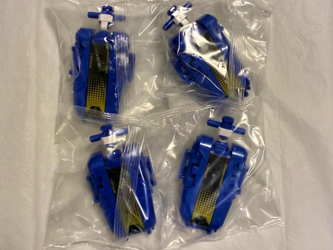 Four sealed blue string launchers for Beyblade X packaged individually in clear plastic bags on a white surface.