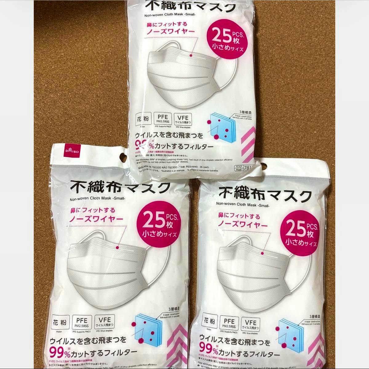 Three sealed packs of small non-woven cloth masks (25 pieces each) shown on a cork background.
