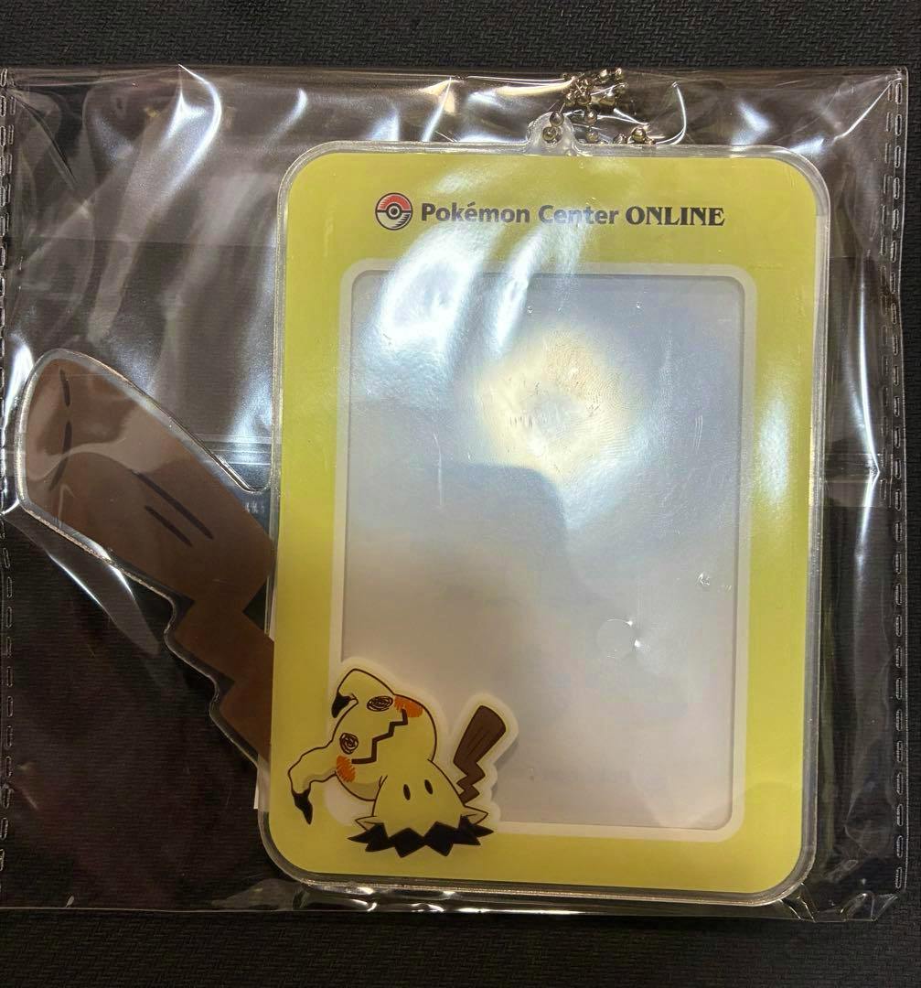 Plastic card case with a yellow border and a Mimikyu character design shown sealed in clear packaging.