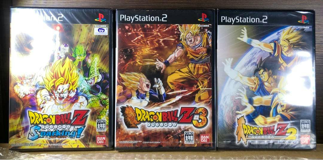 Three sealed PlayStation 2 Dragon Ball Z game cases placed side-by-side on a wooden surface.