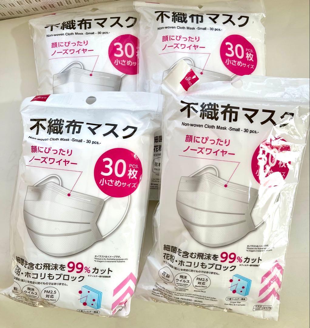 Four sealed packs of non-woven face masks (30 pieces per pack) shown on a surface, front packaging visible.