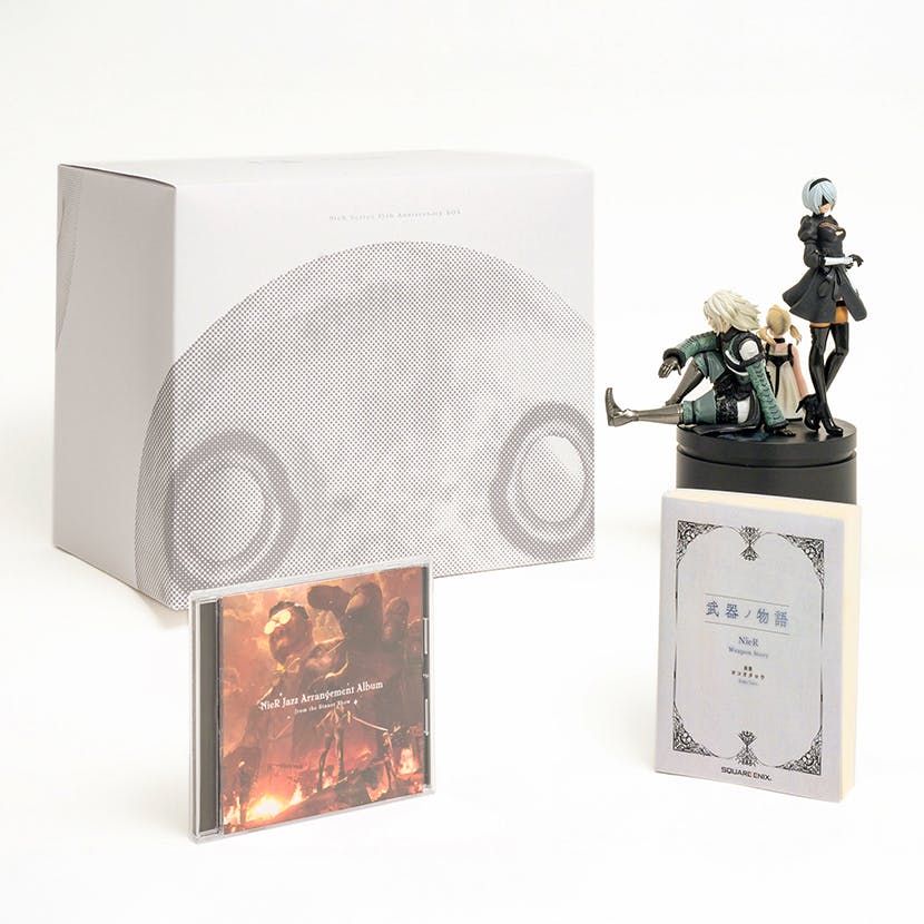 A NieR Series 15th Anniversary box set displayed with its outer box, a CD case, a booklet, and three character figurines on a round base.