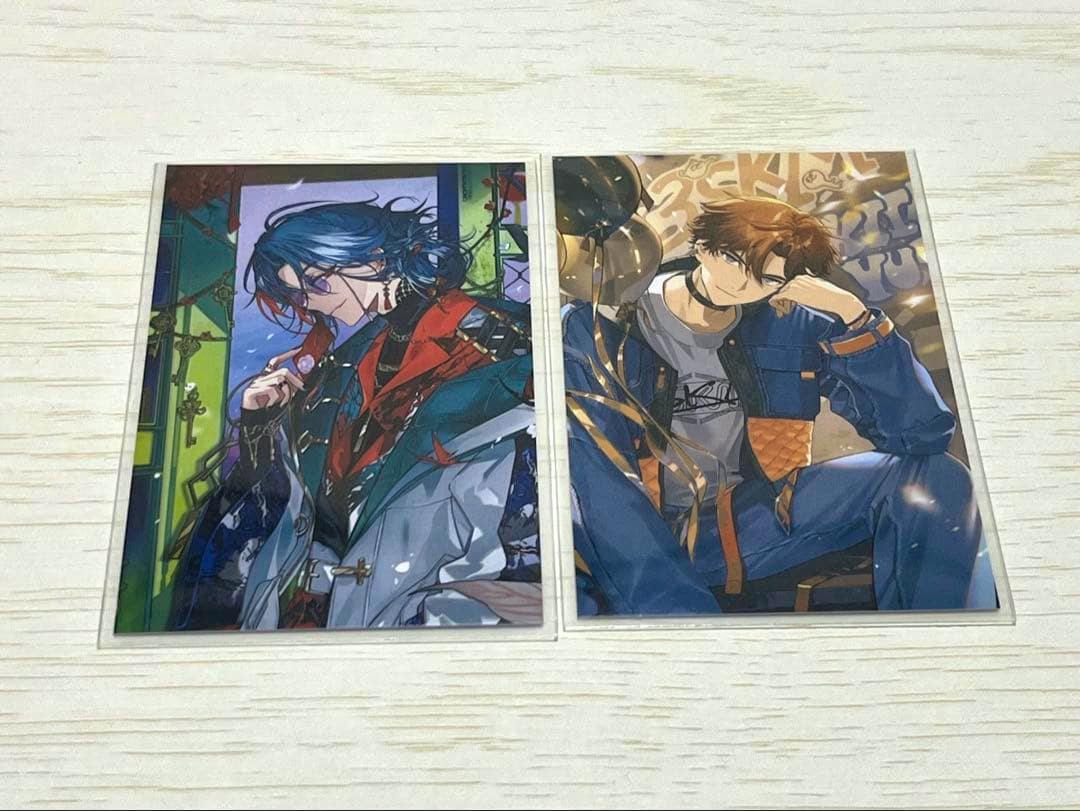 Two photocards from the にじさんじ 北見遊征 魁星 ノスタルジアコレクション displayed side by side on a light wood surface.