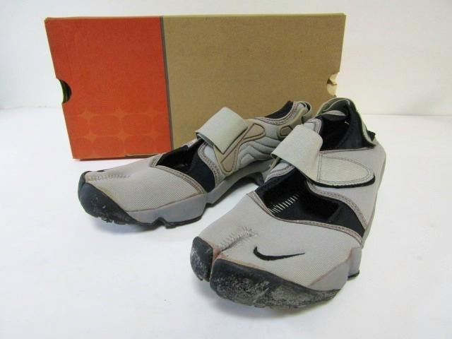 Medium grey Nike Air Rift split-toe shoes displayed on a white surface with the shoebox behind them.