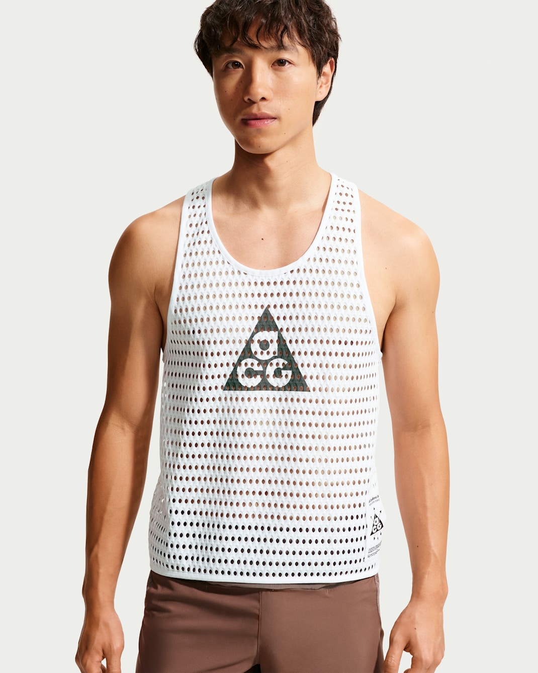 Male model wearing a white ACG Radical AirFlow mesh tank top with perforated pattern and triangular logo.
