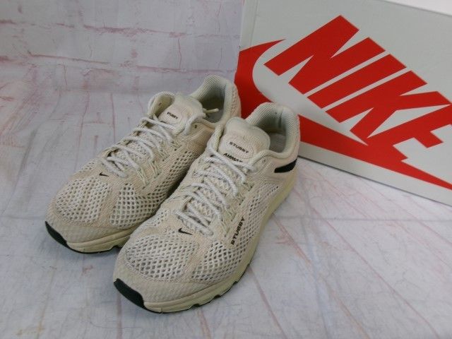 Pair of beige Nike Air Max sneakers displayed in front of a Nike shoebox.
